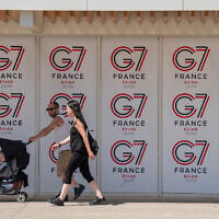 People walk past a G7 banner in Evian-les-Bains, eastern France, on May 28 , 2026, where the G7 summit is set to take place June 15–17. (AP Photo/Baz Ratner)