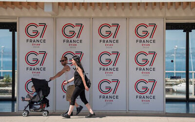 People walk past a G7 banner in Evian-les-Bains, eastern France, on May 28 , 2026, where the G7 summit is set to take place June 15–17. (AP Photo/Baz Ratner)