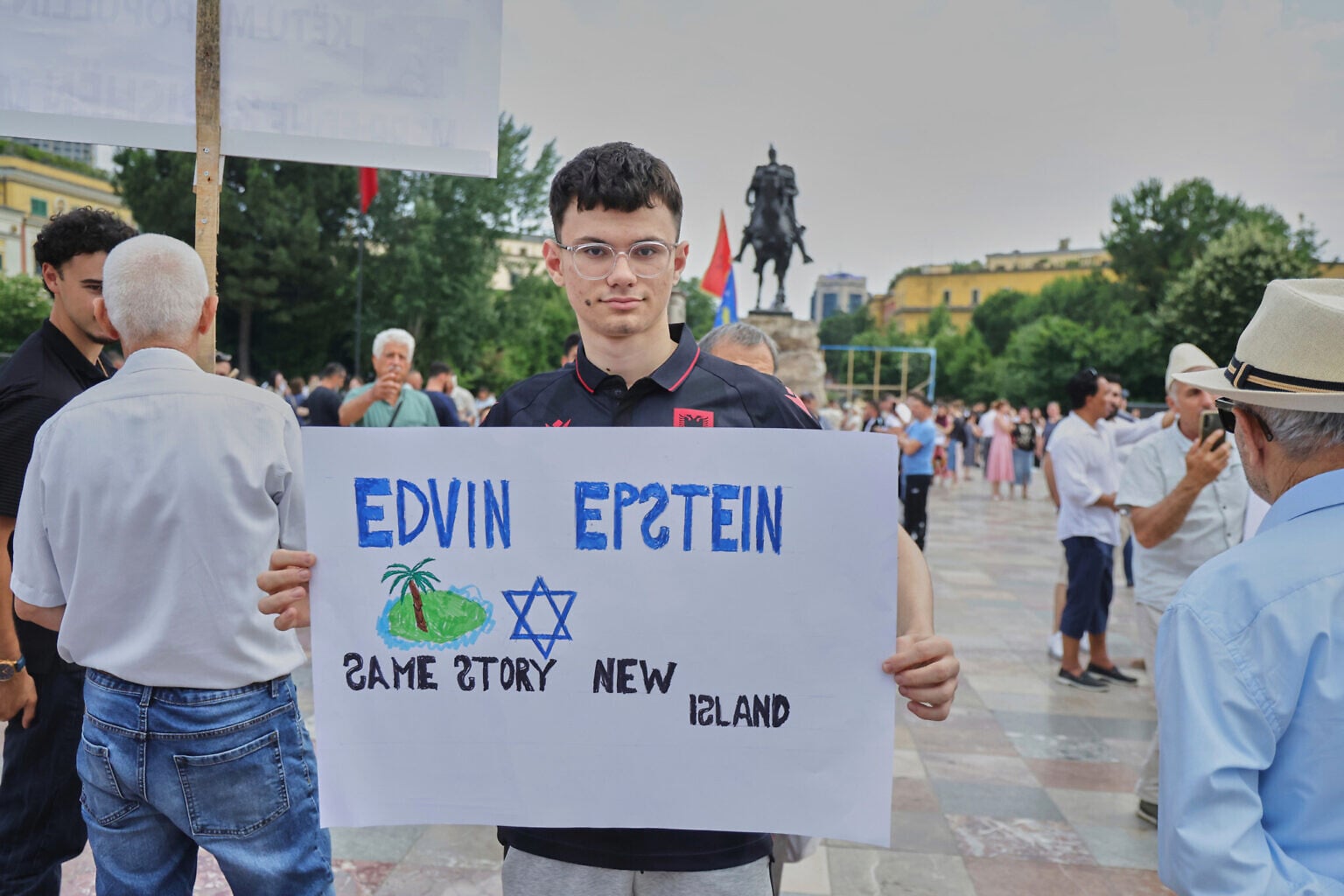 A protester holds an antisemitic placard during a demonstration in Tirana, Albania, June 3, 2026, opposing a luxury coastal development project linked to Jared Kushner and Ivanka Trump. (AP/Hameraldi Agolli)