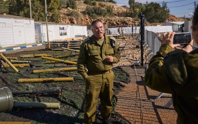 Avichay Adraee, the Israeli military’s Arabic language spokesman, stands beside weapons the army says were seized from Hezbollah in Lebanon, at an army base in northern Israel, December 23, 2024. (AP Photo/Ohad Zwigenberg)