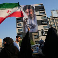 A woman holds up an Iranian flag in front of a banner showing a portrait of the Supreme Leader Ayatollah Mojtaba Khamenei, during a street festival celebrating the Muslim Shiite holiday of Eid al-Ghadir, in Tehran, Iran, June 4, 2026. (AP Photo/Vahid Salemi)