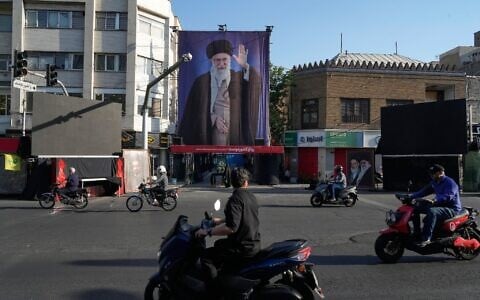 Motorbikes drive near the residence where the late Iranian Supreme Leader Ayatollah Ali Khamenei, shown on a banner, was killed in US and Israeli strikes on February 28, in Tehran, Iran, Saturday, June 6, 2026. (AP Photo/Vahid Salemi)