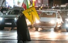 A woman carries an Iranian flag and a flag of Lebanon's Hezbollah terror group while walking toward a pro-government gathering in Tehran, Iran, June 7, 2026. (AP Photo/Vahid Salemi)