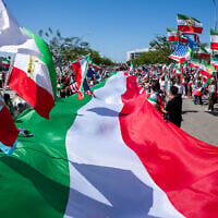 People carry a giant pre-revolutionary Iranian flag during a protest in reaction to FIFA's ban on the flag inside World Cup stadiums, June 7, 2026, in Inglewood, California (AP Photo/Benjamin Hanson)