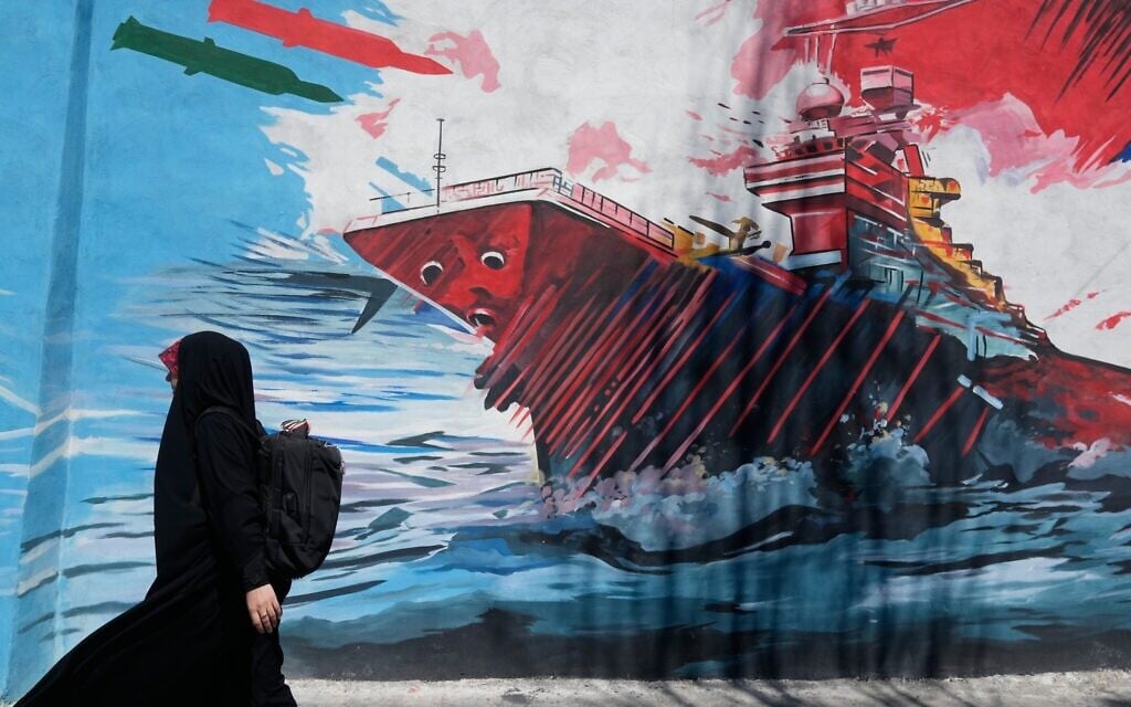 A woman walks past a mural depicting a US aircraft carrier under missile attack in downtown Tehran, Iran,, June 8, 2026. (AP Photo/Vahid Salemi)