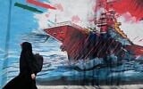 A woman walks past a mural depicting a US aircraft carrier under missile attack in downtown Tehran, Iran,, June 8, 2026. (AP Photo/Vahid Salemi)
