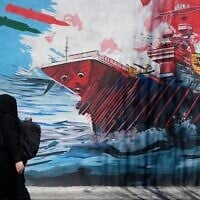 A woman walks past a mural depicting a US aircraft carrier under missile attack in downtown Tehran, Iran,, June 8, 2026. (AP Photo/Vahid Salemi)