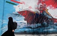 A woman walks past a mural depicting a US aircraft carrier under missile attack in downtown Tehran, Iran,, June 8, 2026. (AP Photo/Vahid Salemi)