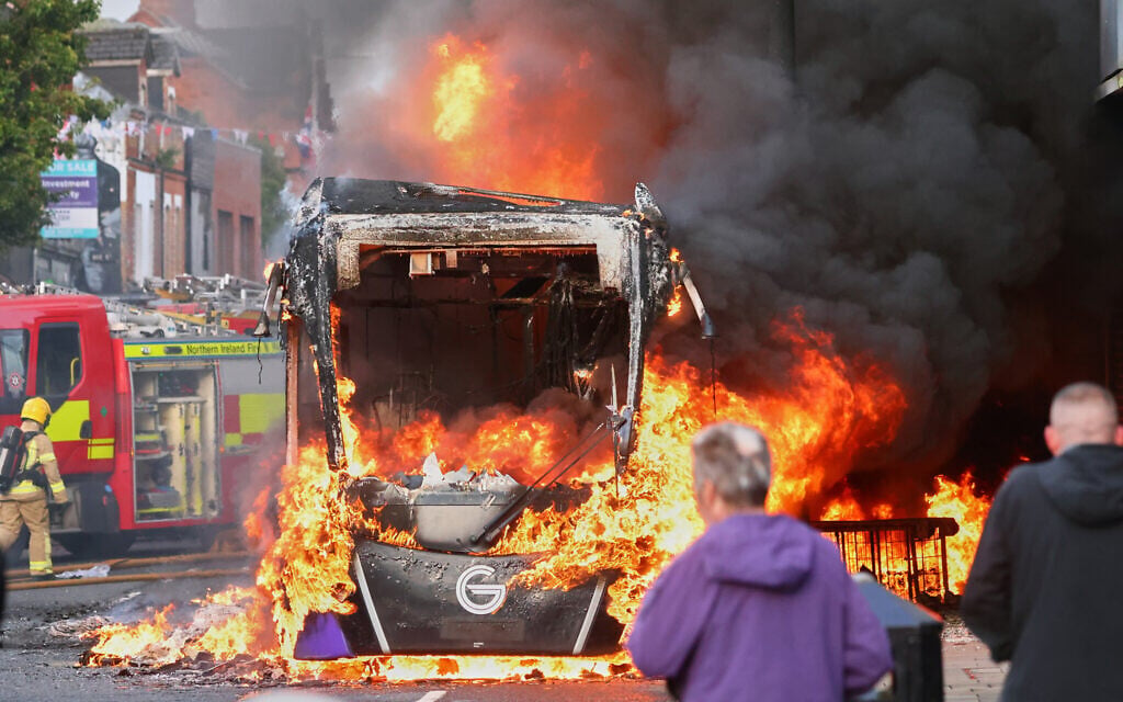 People watch as firemen arrive to put out vehicle that was set alight during a protest in East Belfast following a stabbing in Belfast, June 9, 2026. (AP Photo/Peter Morrison)