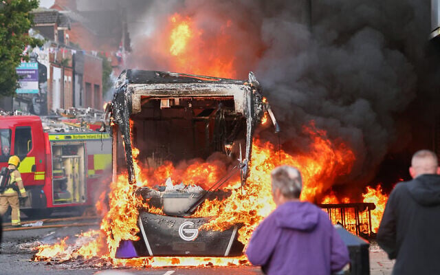 People watch as firemen arrive to put out vehicle that was set alight during a protest in East Belfast following a stabbing incident in Belfast, June 9, 2026. (Peter Morrison/AP) People watch as firemen arrive to put out vehicle that was set alight during a protest in East Belfast following a stabbing incident in Belfast, June 9, 2026. (Peter Morrison/AP)