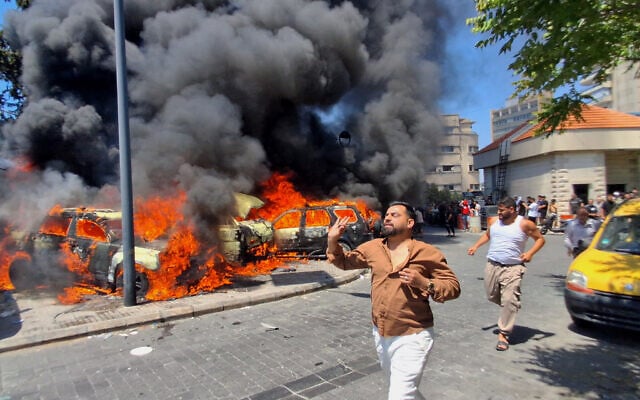 People run in front of burned cars that were attacked in an Israeli airstrike in the southern port city of Sidon, Lebanon, June 10, 2026. (AP Photo/Mohammed Zaatari)