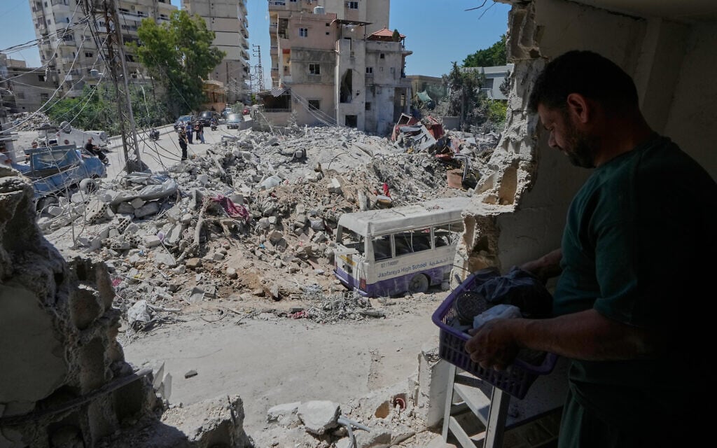 A man collects personal belongins from his house in front of a destroyed building that was hit in an Israeli airstrike, in the southern port city of Tyre, Friday, June 12, 2026. (AP Photo/Mohammed Zaatari)