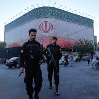 Policemen walk in front of a huge banner showing Iranian flag at the Islamic Revolution square in Tehran, Iran, June 14, 2026. (AP Photo/Vahid Salemi)