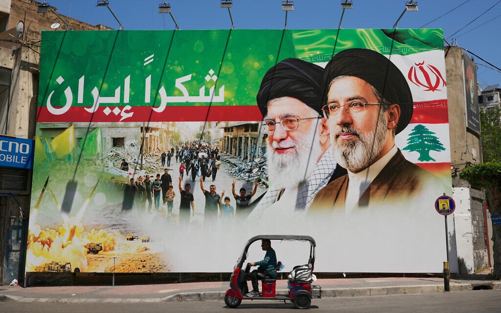 A man rides a scooter past a giant billboard that shows the former Iranian leader Ali Khamenei, center, and his son, Supreme Leader Ayatollah Mojtaba Khamenei, with Arabic writing that reads: "Thank you Iran," in Dahiyeh, Beirut's southern suburbs, Lebanon, June 15, 2026. (AP Photo/Hussein Malla)
