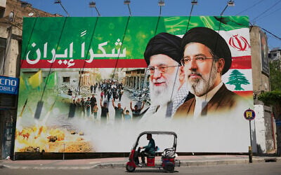 A man rides a scooter past a giant billboard that shows the former Iranian leader Ali Khamenei, center, and his son, Supreme Leader Ayatollah Mojtaba Khamenei, with Arabic writing that reads: "Thank you Iran," in Dahiyeh, Beirut's southern suburbs, Lebanon, June 15, 2026. (AP Photo/Hussein Malla)