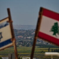 Israeli and Lebanese flags are seen in an area near the border, backdropped by destroyed buildings in southern Lebanon as viewed from northern Israel, June 15, 2026. (Leo Correa/AP)