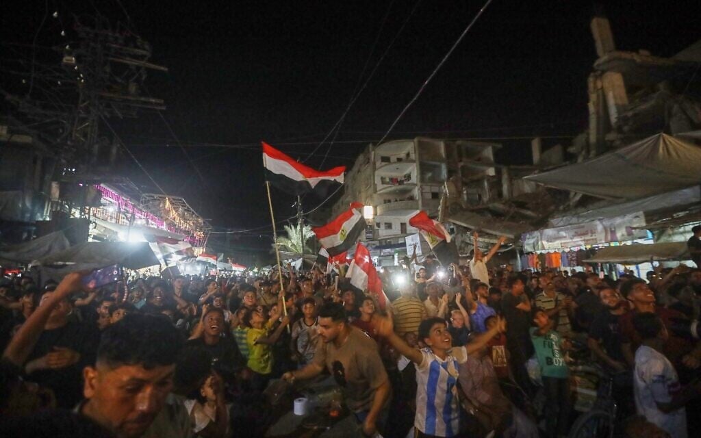 A crowd, some waving Egyptian flags, watches the Egypt-Belgium World Cup match on a giant screen in Nuseirat, central Gaza Strip, June 15, 2026. (AP/Yousef Al Zanoun)