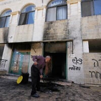 A man clears the rubble as writing in Hebrew on the wall reads "revenge, regards to the arrested, people, wake up," at one of the West Bank mosques that were vandalized and partly set on fire by Israeli settlers overnight, in the village of Jiljilya, north of Ramallah, June 17, 2026. (AP Photo/Majdi Mohammed)