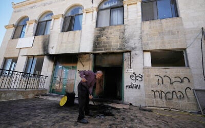 A man clears the rubble as writing in Hebrew on the wall reads "revenge, regards to the arrested, people, wake up," at one of the West Bank mosques that were vandalized and partly set on fire by Israeli settlers overnight, in the village of Jiljilya, north of Ramallah, June 17, 2026. (AP Photo/Majdi Mohammed)
