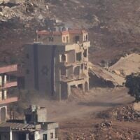 An Israeli flag covers a part of a damaged building in southern Lebanon seen from northern Israel, June 18, 2026. (AP Photo/Ariel Schalit)