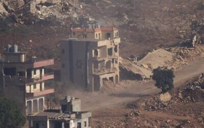 An Israeli flag covers a part of a damaged building in southern Lebanon seen from northern Israel, June 18, 2026. (AP Photo/Ariel Schalit)