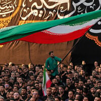 A man waves an Iranian flag as people beat their chests during a religious mourning ceremony in Tehran, Iran, on June 18, 2026. (AP Photo/Vahid Salemi)