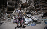 A man holds his daughter's bicycle recovered from his barbershop as he searches for belongings in the rubble of the shop, damaged in an Israeli strike, in the southern port city of Tyre, Lebanon, June 19, 2026. (AP Photo/Hassan Ammar)