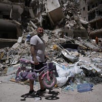 A man holds his daughter's bicycle recovered from his barbershop as he searches for belongings in the rubble of the shop, damaged in an Israeli strike, in the southern port city of Tyre, Lebanon, June 19, 2026. (AP Photo/Hassan Ammar)