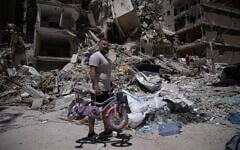 A man holds his daughter's bicycle recovered from his barbershop as he searches for belongings in the rubble of the shop, damaged in an Israeli strike, in the southern port city of Tyre, Lebanon, June 19, 2026. (AP Photo/Hassan Ammar)