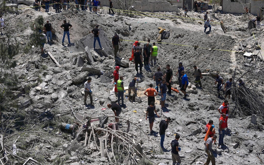 Rescue workers and people search for victims under the rubble of a destroyed building that was hit in an Israeli airstrike in Qannarit village, southern Lebanon June 20, 2026. (AP Photo/Mohammed Zaatari)