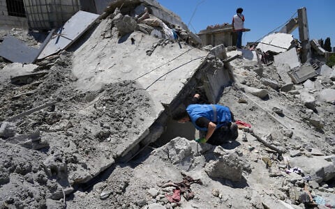 A rescue worker searches for victims under the rubble of a destroyed building that was hit in an Israeli airstrike in Qannarit village, southern Lebanon, June 20, 2026. (AP Photo/Mohammed Zaatari)