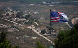 A joint Israel-US flag stands against a backdrop of destroyed buildings in southern Lebanon, as seen from northern Israel, June 21, 2026. (AP Photo/Ohad Zwigenberg)