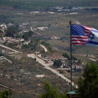 A joint Israel-US flag stands against a backdrop of destroyed buildings in southern Lebanon, as seen from northern Israel, June 21, 2026. (AP Photo/Ohad Zwigenberg)