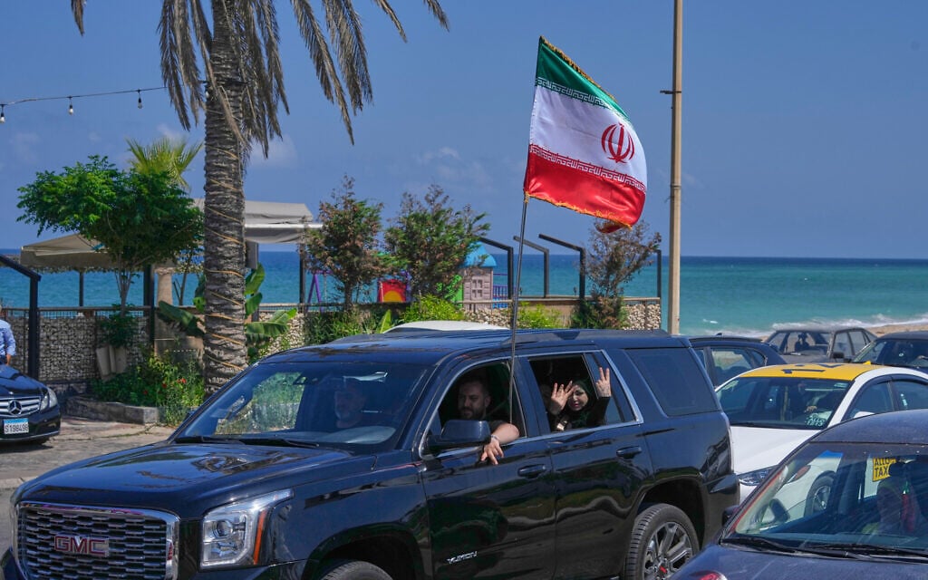 Displaced residents wave an Iranian flag as they return to their village following a ceasefire between Israel and Hezbollah in the southern port city of Sidon, Lebanon, Tuesday, June 23, 2026. (AP Photo/Mohammed Zaatari)