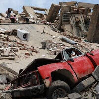A vehicle is crushed at a building that collapsed after earthquakes struck La Guaira, Venezuela,June 25, 2026. (AP Photo/Javier Campos)