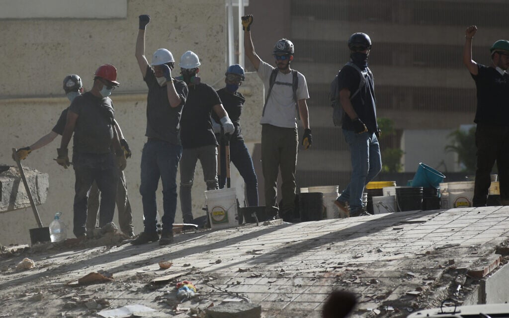Rescue workers gesture for silence as they search for survivors in a building that collapsed after earthquakes struck Caracas, Venezuela, a day earlier, June 25, 2026. (AP Photo/Jonathan Lanza)