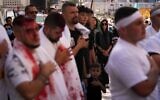 A woman watches as Lebanese Shiites beat their chests and bleed from self-inflicted ceremonial head wounds during Ashura, when Shiites commemorate the martyrdom of Imam Hussein, the grandson of the Prophet Muhammad, amid buildings destroyed by Israeli strikes in Nabatiyeh, southern Lebanon, June 26, 2026. (AP Photo/Hassan Ammar)