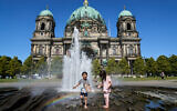Children cool off in a fountain in front of the Berlin Cathedral during a summer heat wave, on June 26, 2026. (AP Photo/Ebrahim Noroozi)