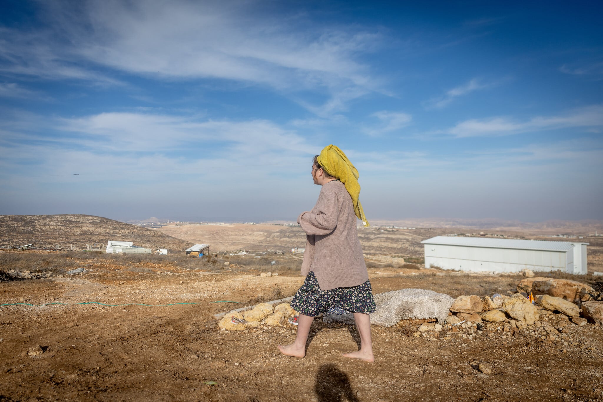 A woman walks near Tzur Misgavi, an illegal outpost in Gush Etzion, in the West Bank, November 17, 2025. (Chaim Goldberg/Flash90)