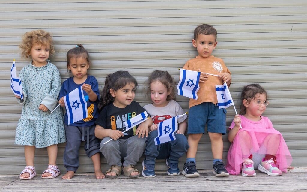 Children play with Israeli flags ahead of Israel's 78th Independence Day, at Kobi Kindergarden in Moshav Yashresh, on April 16, 2026. (Yossi Aloni/Flash90)