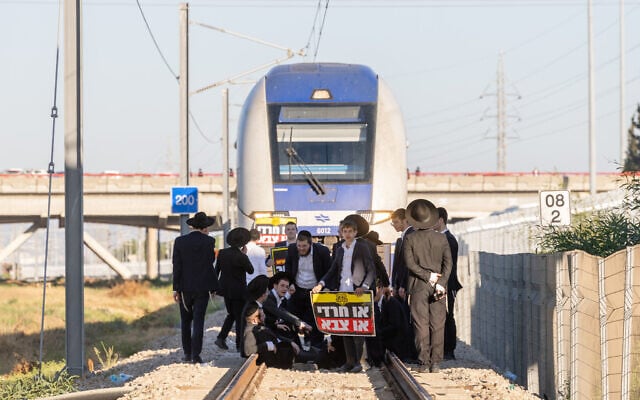 Protesters stand in front of a train on the railway tracks near the Ganot Interchange in central Israel as they demonstrate against the arrest of ultra-Orthodox draft evaders, on June 1, 2026. (Chaim Goldberg/Flash90) Protesters stand in front of a train on the railway tracks near the Ganot Interchange in central Israel as they demonstrate against the arrest of ultra-Orthodox draft evaders, on June 1, 2026. (Chaim Goldberg/Flash90)