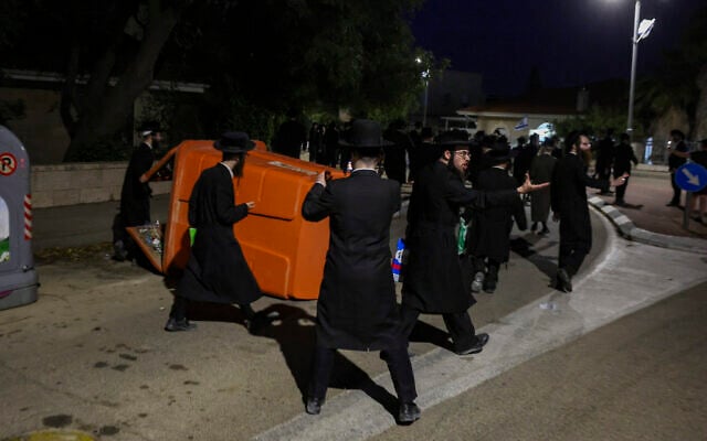 Haredi demonstrators push over a dumpster while rioting outside the home of Supreme Court Deputy Chief Justice Noam Sohlberg in the settlement of Alon Shvut, June 3, 2026. (Chaim Goldberg/Flash90)