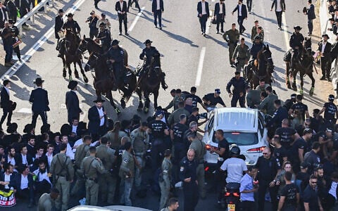 Ultra-Orthodox Jewish men block a road and clash with police during a protest against the jailing of yeshiva students who failed to comply with an army recruitment order, at Ganot Junction near Tel Aviv, June 11, 2026. (Avshalom Sassoni/Flash90)