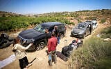 People survey damage caused to Palestinian vehicles by violent settlers who attacked a group of Palestinians and Jewish activists near Halhul, in the Hebron area of the West Bank, on June 15, 2026. (Wisam Hashlamoun/Flash90)