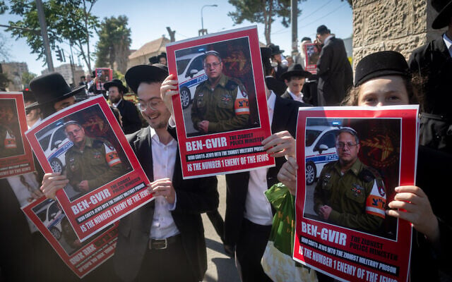 Ultra-Orthodox Jewish men holding mocking posters of National Security Minister Itamar Ben Gvir on their way to attend a rally against the imprisonment of ultra-Orthodox draft evaders, in the Geula neighborhood of Jerusalem, June 24, 2026. (Chaim Goldberg/Flash90)
