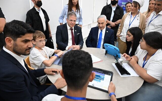 Education Minister Yoav Kisch (left of center) and Prime Minister Benjamin Netanyahu (right of center) sit with students at the Dekel Vilnai Middle School in the settlement of Ma’ale Adumim in the West Bank, to launch an AI-powered English language program on June 11, 2026. (Haim Zach / GPO)