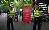 Police patrol as a protestor stands near a banner outside of a venue where Ye, the rapper formerly known as Kanye West, will perform, in Arnhem, Netherlands, June 6, 2026. (Mouneb Taim/AP)