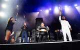 French paralympic athlete Helios Latchoumanaya (R) holds the paralympic flame flanked by French-Iranian writer Marjane Satrapi (2nd L) and French DJ Barbara Butch (C) during the 20th edition of the Rock en Seine music festival, in Saint-Cloud, outside Paris, on August 25, 2024. (Anna KURTH/AFP)