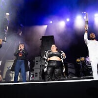 French paralympic athlete Helios Latchoumanaya (R) holds the paralympic flame flanked by French-Iranian writer Marjane Satrapi (2nd L) and French DJ Barbara Butch (C) during the 20th edition of the Rock en Seine music festival, in Saint-Cloud, outside Paris, on August 25, 2024. (Anna KURTH/AFP)