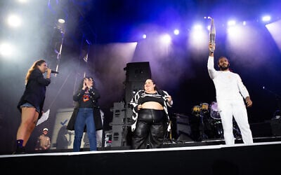 French paralympic athlete Helios Latchoumanaya (R) holds the paralympic flame flanked by French-Iranian writer Marjane Satrapi (2nd L) and French DJ Barbara Butch (C) during the 20th edition of the Rock en Seine music festival, in Saint-Cloud, outside Paris, on August 25, 2024. (Anna KURTH/AFP) French paralympic athlete Helios Latchoumanaya (R) holds the paralympic flame flanked by French-Iranian writer Marjane Satrapi (2nd L) and French DJ Barbara Butch (C) during the 20th edition of the Rock en Seine music festival, in Saint-Cloud, outside Paris, on August 25, 2024. (Anna KURTH/AFP)
